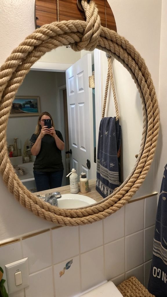 a round bathroom mirror framed with nautical rope.